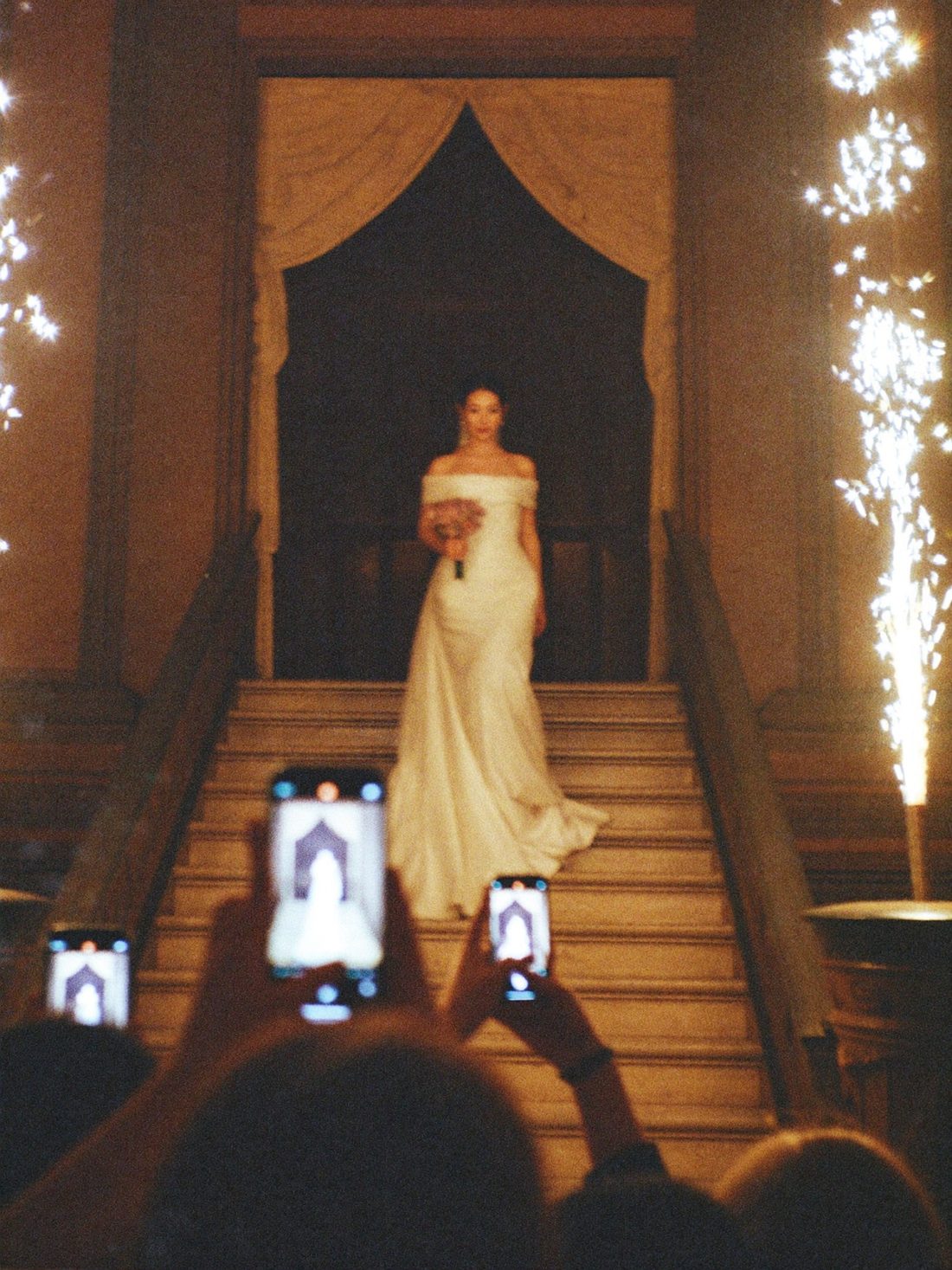 Bride descending a staircase between spark fountains