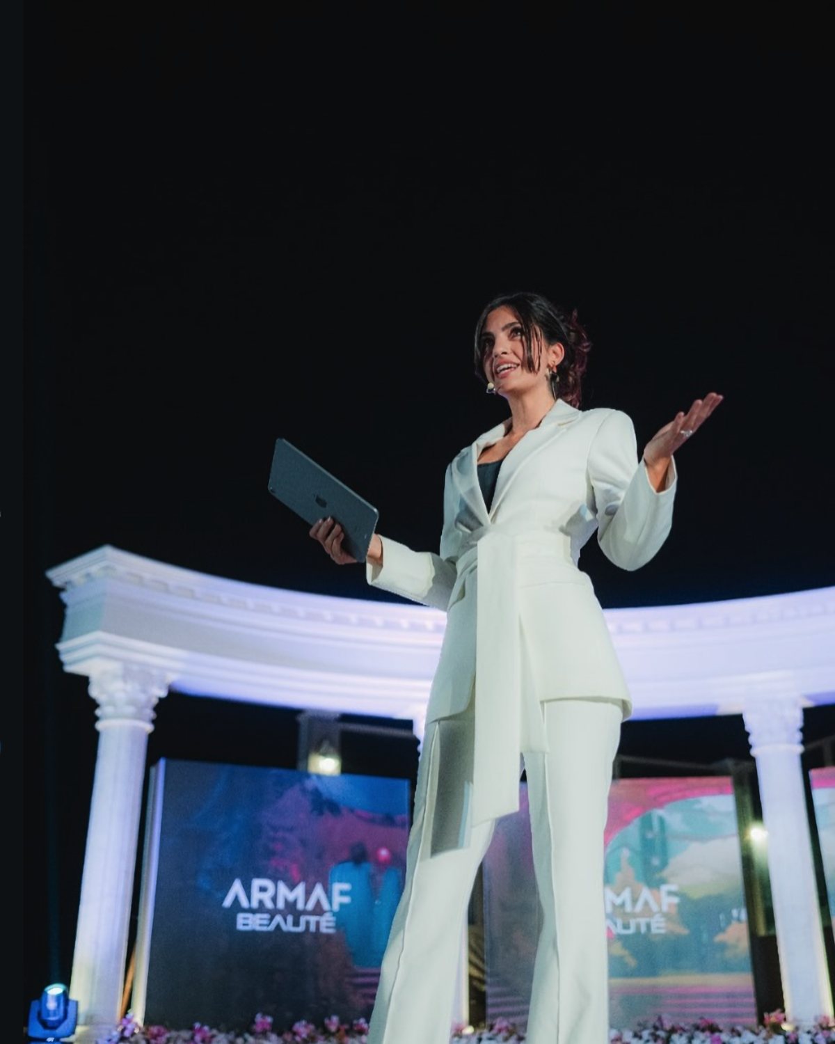 Event host in a white suit presenting on stage at a beauty brand launch