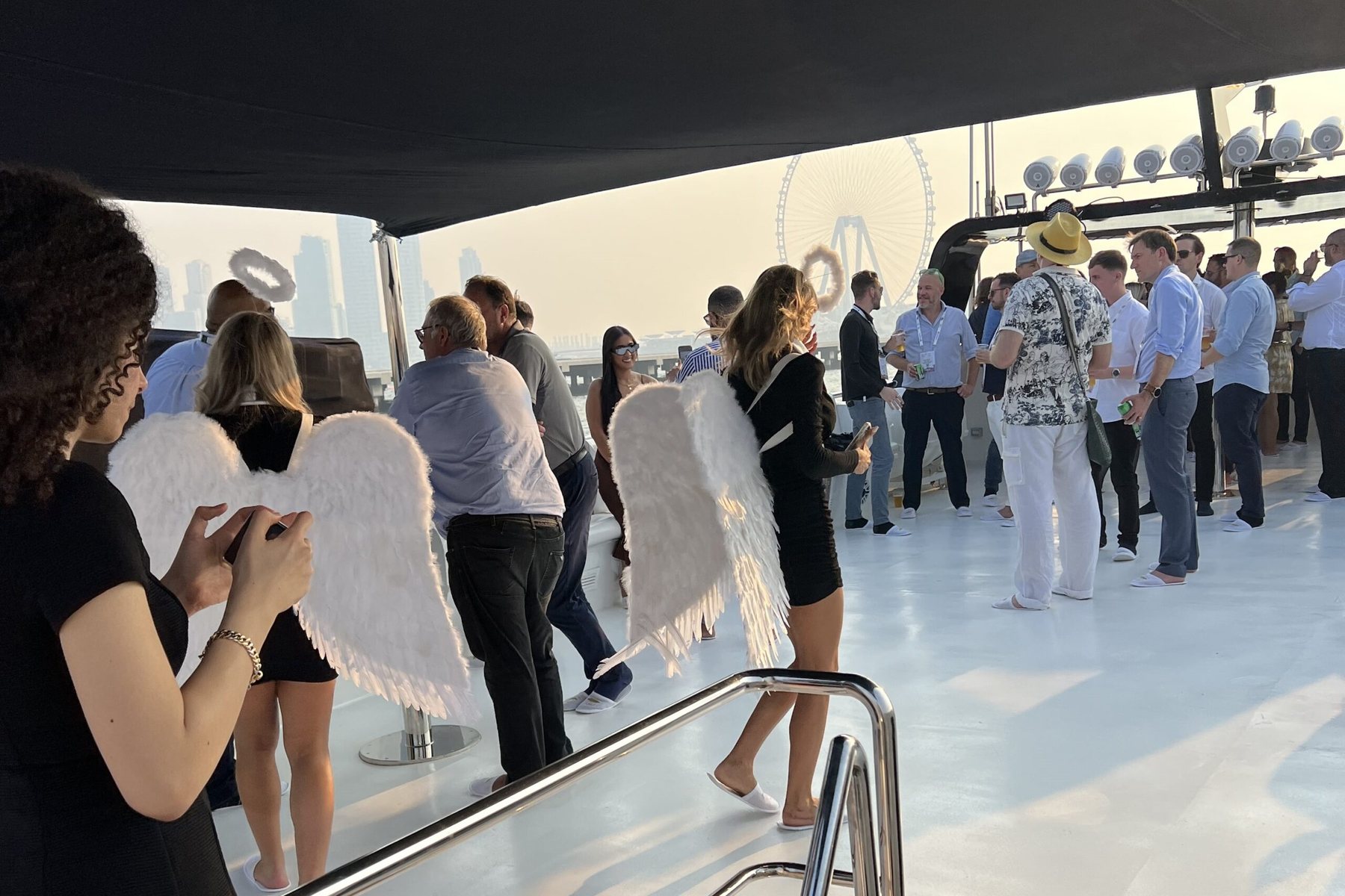 Corporate guests on a yacht deck with Ain Dubai in the distance